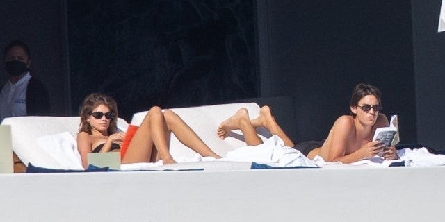 Kaia Gerber lounged next two a young unidentified guy who was reading a book. 