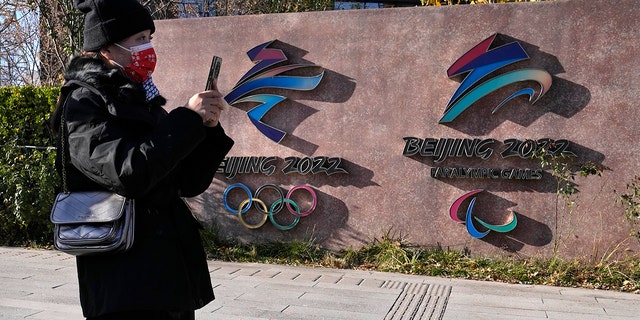 A visitor to the Shougang Park walks past the logos for the Beijing Winter Olympics and Paralympics in Beijing, China, Tuesday, Nov. 9, 2021. 