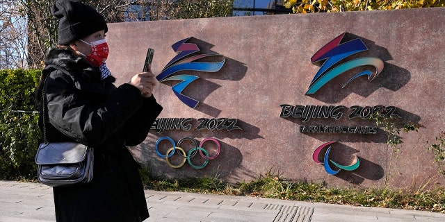 A visitor to the Shougang Park walks past the logos for the Beijing Winter Olympics and Paralympics in Beijing, China, Tuesday, Nov. 9, 2021.