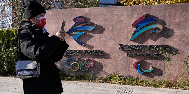 A visitor to the Shougang Park walks past the logos for the Beijing Winter Olympics and Paralympics in Beijing, China, Tuesday, Nov. 9, 2021. 