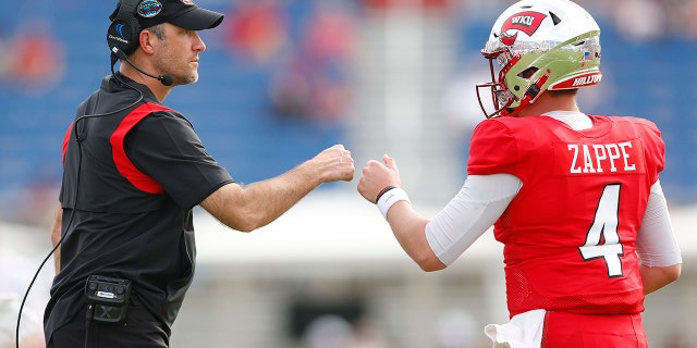 BOCA RATON, FLORIDA - DECEMBER 18: Head coach Tyson Helton of the Western Kentucky Hilltoppers fist bumps Bailey Zappe #4 against the Appalachian State Mountaineers during the second half of the RoofClaim.com Boca Raton Bowl at FAU Stadium on December 18, 2021 in Boca Raton, Florida.