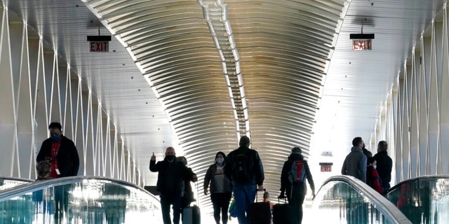 Travelers pull luggage while walking on a pedestrian bridge between terminals at Logan International Airport, in Boston., Wednesday, Nov. 24, 2021, the day before Thanksgiving. (AP Photo/Steven Senne) 