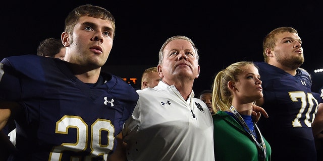 Sam Kohler (29) head coach Brian Kelly, Grace Kelly and Hunter Bivin (70) of the Notre Dame Fighting Irish sing the alma mater following a loss to the Michigan State Spartans Sept. 17, 2016 in South Bend, Ind.  