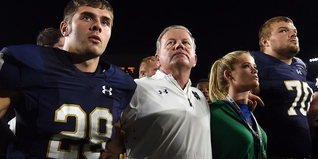 Sam Kohler (29) head coach Brian Kelly, Grace Kelly and Hunter Bivin (70) of the Notre Dame Fighting Irish sing the alma mater following a loss to the Michigan State Spartans Sept. 17, 2016 in South Bend, Ind.  