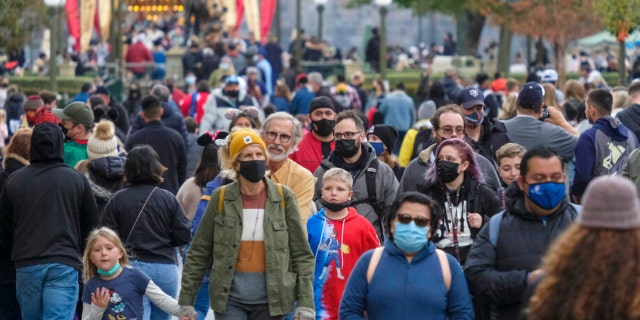 Visitors wearing face masks walk down Main Street USA at Disneyland in Anaheim, California, Monday, Dec. 27, 2021. (AP Photo/Ringo H.W. Chiu)
