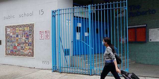 A woman walks by the closed Roberto Clemente Public School 15 in New York City on Aug. 7, 2020.