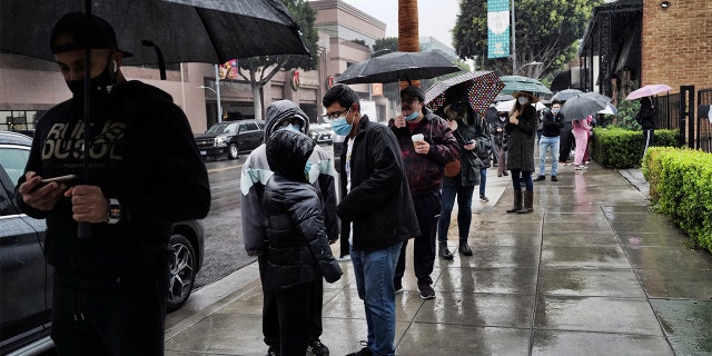 People stand in the rain as they wait in line for a COVID-19 test in Beverly Hills, California, Thursday, Dec. 23, 2021.