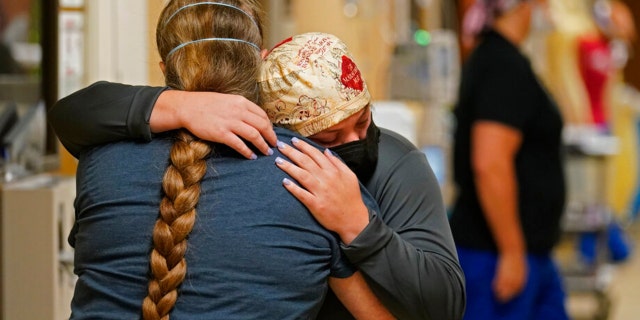 ICU nurse Melinda Hunt, facing, hugs the sister of a COVID-19 patient she had been caring for, who had just passed away