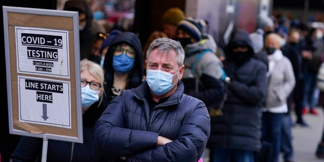 People wait in line at a COVID-19 testing site in New York's Times Square. More than a year after the vaccine was rolled out, new cases of COVID-19 in the U.S. have soared to their highest level.