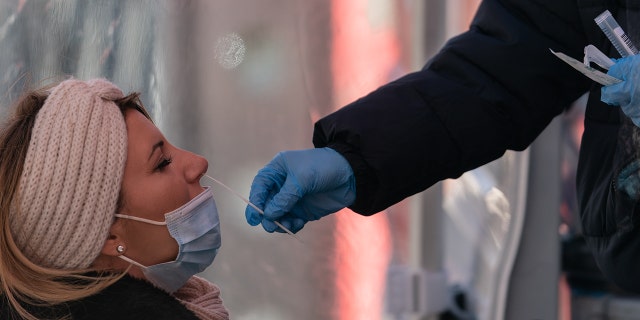 一名医护人员在美国纽约时代广场的移动测试站点进行 Covid-19 测试鼻拭子 Gina Moon/Bloomberg via Getty Images