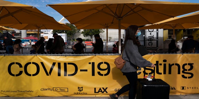 Travelers wait in line to get tested for COVID-19 at Los Angeles International Airport in Los Angeles on Monday.
