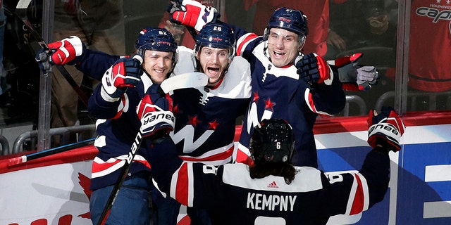 Washington Capitals' Nic Dowd, center, celebrates with teammates Carl Hagelin, left, Garnet Hathaway, right, and Michal Kempny (6) after scoring a goal against Nashville Predators goalie Juuse Saros (74) during the first period of an NHL hockey game, Wednesday, Dec. 29, 2021, in Washington.