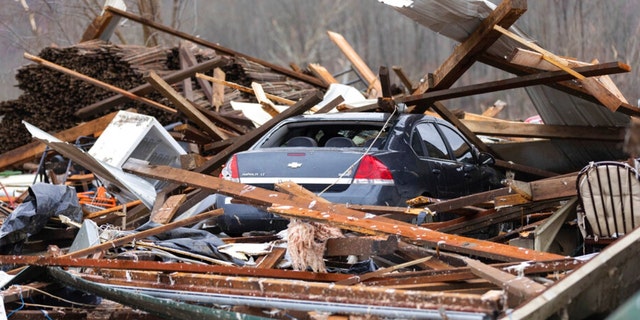 A car sits under a house destroyed by a tornado in Campbellsville, Ky