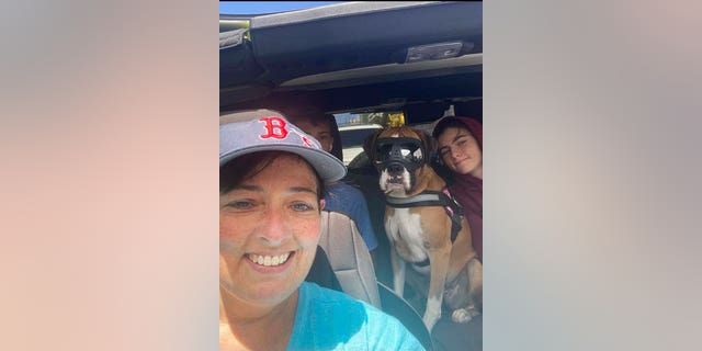This 2021 photo provided by Cheri Burness shows Burness and her family, including dog Lilikoi, in a car in Honolulu. 