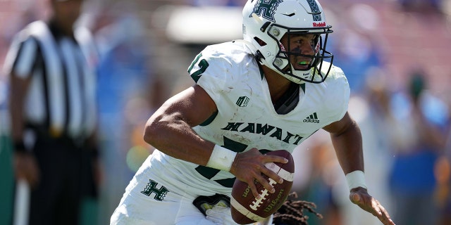 八月 28, 2021; Pasadena, 加利福尼亚州, 美国; Hawaii Rainbow Warriors quarterback Chevan Cordeiro (12) is pressured by UCLA Bruins linebacker Carl Jones Jr. (35) in the second half at Rose Bowl.