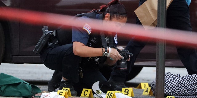 A Chicago police officer processes a crime scene in a strip mall at 83rd Street and Holland Road after Jamari Williams, 15, was fatally shot on Sept. 21, 2021.