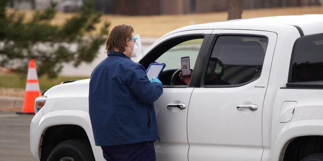 Um funcionário verifica a entrada de um cliente em uma estação de testes COVID-19 drive-up fora do centro de justiça quinta-feira, 9 de dezembro de 2021, em Castle Rock, Colorado. 