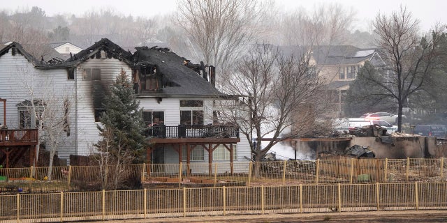The remains of homes smolder Friday after wildfires ripped through a development in Superior, Colo.