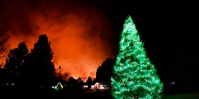 A Christmas tree is still lit with Christmas lights as fires rage in the background on December 30, 2021 in Louisville, Colorado.