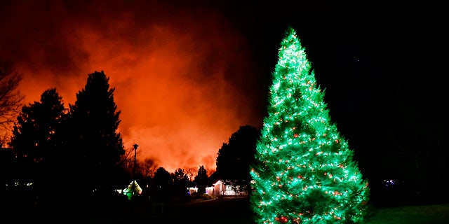 A Christmas tree is still lit with Christmas lights as fires rage in the background on December 30, 2021 in Louisville, Colorado.  (Photo by Helen H. Richardson/MediaNews Group/The Denver Post via Getty Images)