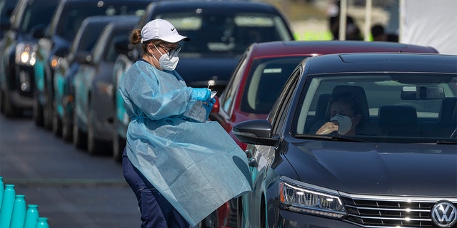 A health care worker conducts a test at a drive-thru COVID-19 testing site at the Dan Paul Plaza on Dec. 29, 2021 in Miami, Florida. In response to the increasing demand for COVID-19 tests, Miami-Dade County opened two new testing sites and expanded hours at the Zoo Miami testing location.