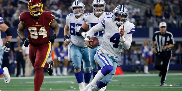 Dallas Cowboys quarterback Dak Prescott (4) runs the ball for a first down while Washington Football Team defensive tackle Daron Payne (94) chases in the first half of an NFL football game in Arlington, Texas on Sunday December 26, 2021.