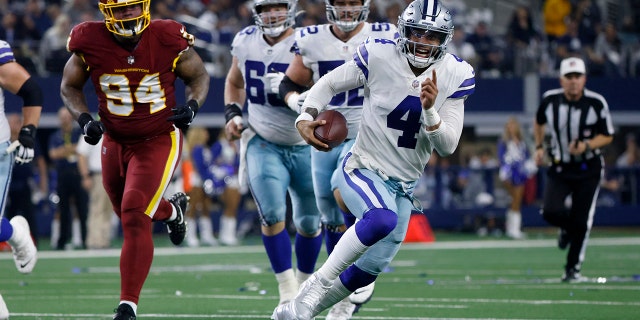 Dallas Cowboys quarterback Dak Prescott (4) runs the ball for a first down as Washington Football Team defensive tackle Daron Payne (94) gives chase in the first half of an NFL football game in Arlington, Texas, Sunday, Dec. 26, 2021.