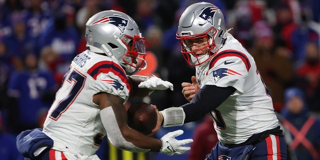 Mac Jones do New England Patriots entrega a bola para Damian Harris (37) do New England Patriots durante o primeiro quarto contra o Buffalo Bills no High Mark Stadium em 6 de dezembro de 2021, em Orchard Park, Nova York. 