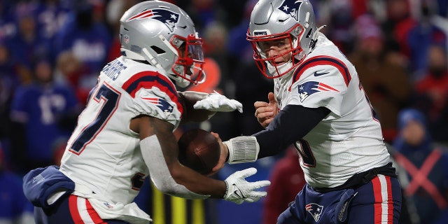 Mac Jones do New England Patriots entrega a bola para Damian Harris (37) do New England Patriots durante o primeiro quarto contra o Buffalo Bills no High Mark Stadium em 6 de dezembro de 2021, em Orchard Park, Nova York. 