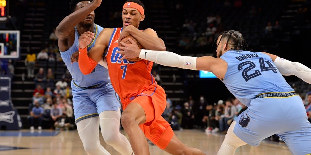 Oklahoma City Thunder forward Darius Bazley (7) drives between Memphis Grizzlies forwards Dillon Brooks (24) and Jaren Jackson Jr. in the first half of an NBA basketball game Thursday, Dec. 2, 2021, in Memphis, Tenn.