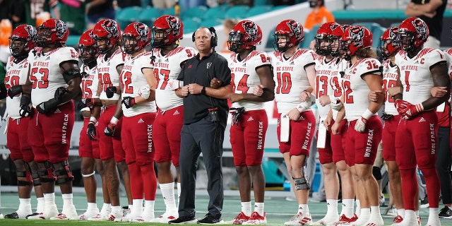 Head coach Dave Doeren of the North Carolina State Wolfpack stands with the team during the national anthem prior to the game against the Miami Hurricanes at Hard Rock Stadium on Oct. 23, 2021, in Miami Gardens, Florida.