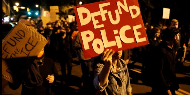 Demonstrators hold a sign reading "Defund the police" during a protest over the death of a Black man, Daniel Prude, after police put a spit hood over his head during an arrest on March 23, in Rochester, New York, U.S. September 6, 2020. REUTERS/Brendan McDermid