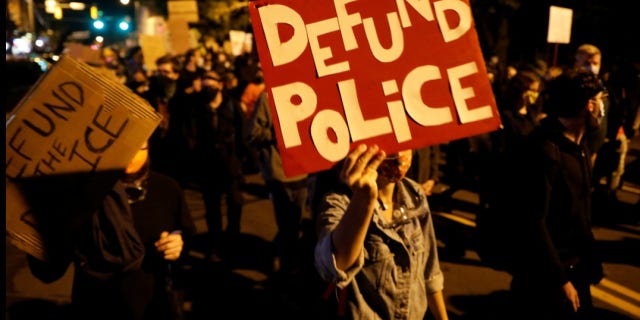 Demonstrators hold a sign reading "Defund the police" during a protest over the death of a Black man, Daniel Prude, after police put a spit hood over his head during an arrest on March 23, in Rochester, New York, Sept. 6, 2020.