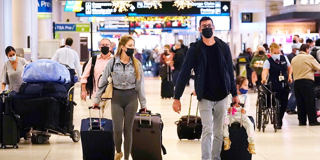 Holiday travelers push their luggage inside Miami International Airport, Tuesday, Nov. 23, 2021, in Miami. (AP Photo/Marta Lavandier)