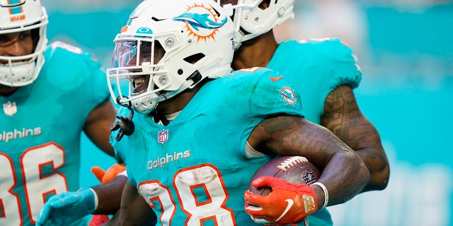 Miami Dolphins running back Duke Johnson (28) is congratulated by teammates after scoring a touchdown during the second half of an NFL football game against the New York Jets, Domenica, Dic. 19, 2021, a Miami Gardens, Fla.