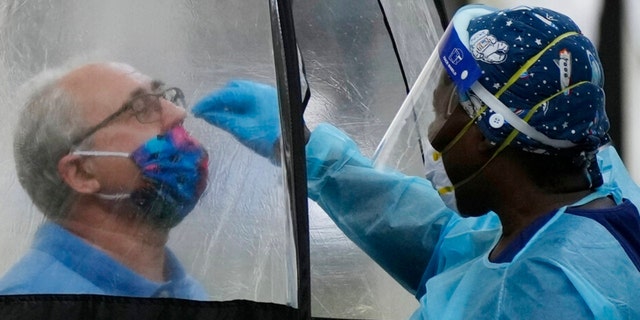 A man is tested for COVID-19, at a walk-up testing site run by Nomi Health, Tuesday, Dec. 28, 2021, in downtown Miami. Officials in Miami-Dade County have opened two new coronavirus testing sites and extended hours at Zoo Miami in response to an increased demand. (AP Photo/Rebecca Blackwell)