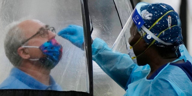 A man is tested for COVID-19, at a walk-up testing site run by Nomi Health, Tuesday, Dec. 28, 2021, in downtown Miami. (AP Photo/Rebecca Blackwell)