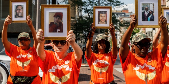 Mothers of Murdered Columbus Children stand at the intersection of High Street and Broad Street while holding pictures of their deceased children. (Stephen Zenner/SOPA Images/LightRocket via Getty Images)