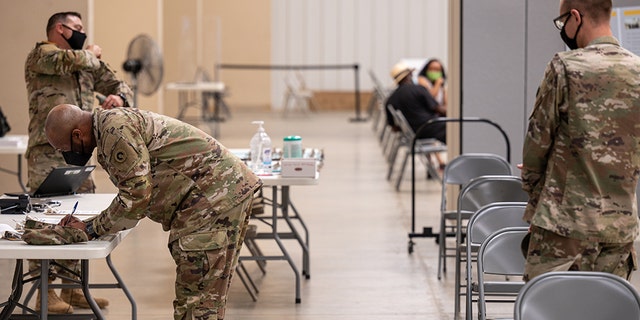 Soldiers file paperwork before being administered their COVID-19 vaccinations by Army Preventative Medical Services Sept. 9, 2021, at Fort Knox, Kentucky. 