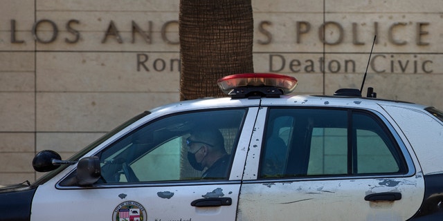 A member of the LAPD sits inside his squad car, parked outside its headquarters on First Street in downtown Los Angeles. (Mel Melcon / Los Angeles Times via Getty Images)