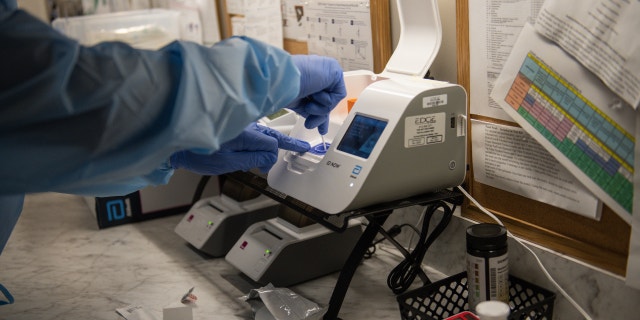 A healthcare worker inserts a Covid-19 rapid test into a machine at the CareNow Denver University urgent care center in Denver, Colorado, U.S., on Tuesday, Nov. 16, 2021. Photographer: Daniel Brenner/Bloomberg