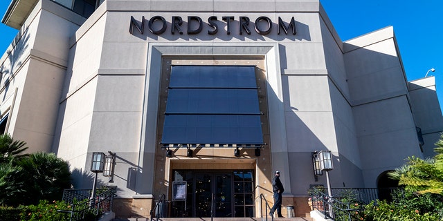 A security guard stands watch outside a Nordstrom store after an organized group of thieves attempted a smash-and-grab attack, Nov. 23, 20201 in Los Angeles.