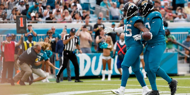 Jaguars James Robinson and Malcom Brown celebrate a touchdown while a security guard tackles a fan that rushed the field during the Houston Texans game on Dec. 19, 2021, at TIAA Bank Field in Jacksonville.