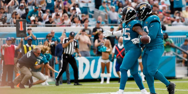 Jaguars James Robinson and Malcom Brown celebrate a touchdown while a security guard tackles a fan that rushed the field during the Houston Texans game on Dec. 19, 2021, at TIAA Bank Field in Jacksonville.