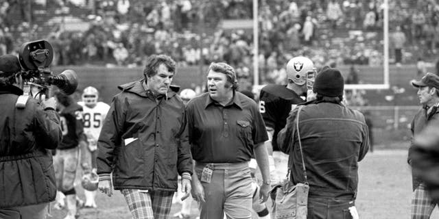 Baş antrenörler Cleveland Browns'tan Forrest Greg (solda) ve Oakland Raiders'tan John Madden, 9 Ekim 1977'de Cleveland, Ohio'da Cleveland Belediye Stadı'nda bir maçın ardından sahayı terk ediyor.  Auckland 26-10 kazandı. 