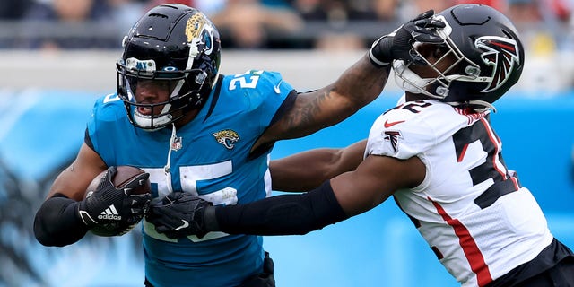 JACKSONVILLE, FLORIDA - NOVEMBER 28: James Robinson #25 of the Jacksonville Jaguars attempts to run past Jaylinn Hawkins #32 of the Atlanta Falcons during the game at TIAA Bank Field on November 28, 2021 in Jacksonville, Florida.