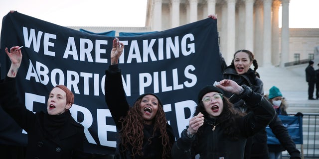 Activists prepare to take an abortion pill while demonstrating in front of the U.S. Supreme Court as the justices hear arguments in Dobbs v. Jackson Women's Health on Dec. 1, 2021, in Washington, D.C.