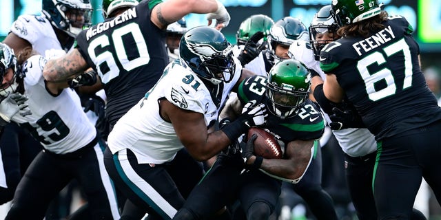 Tevin Coleman (23) of the New York Jets runs the ball and is tackled by Fletcher Cox (91) of the Philadelphia Eagles during the second quarter at MetLife Stadium on Dec. 5, 2021, in East Rutherford, New Jersey. 