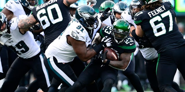 Tevin Coleman (23) of the New York Jets runs the ball and is tackled by Fletcher Cox (91) of the Philadelphia Eagles during the second quarter at MetLife Stadium on Dec. 5, 2021, in East Rutherford, New Jersey. 