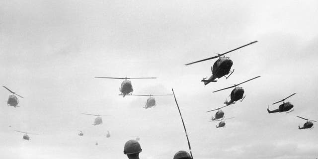 The second wave of combat helicopters of the 1st Air Cavalry Division fly over an RTO and his commander on an isolated landing zone during Operation Pershing during the Vietnam War. (Photo by Patrick Christain/Getty Images)